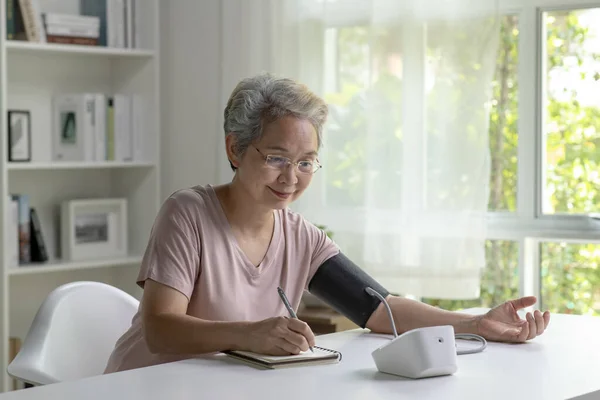 Aziatische Senior Vrouw Meten Bloeddruk Thuis Stockfoto