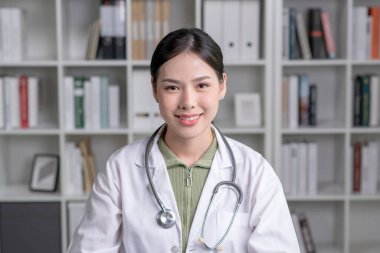 Tıp bürosundaki kameraya bakan güzel gülümseyen Asyalı kadın doktorun portresi. Sağlık konsepti, sağlık sigortası, kopyalama alanı.