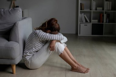 Genç Asyalı kadın evde oturmuş üzgün, yorgun ve endişeli zihinsel sağlıkta depresyon geçiriyor. Bir kadın zihinsel sağlık sorunları yaşıyor..