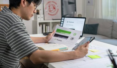 Male Asian graphic designer working in an office studio, choosing color palettes, designing logos and showcasing the corporate identity and logo design process.	