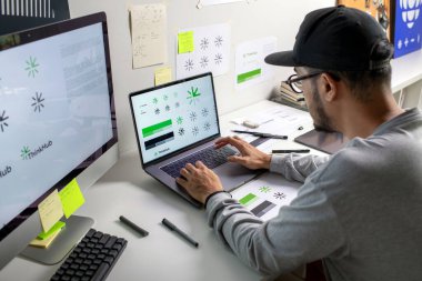 Asian graphic designer making notes on logo designs, using computers, designing logos, and showcasing the corporate identity and logo design process.	