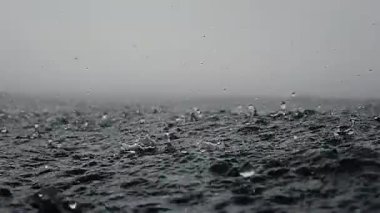 Sonsuz okyanusa yağmur damlaları düşer, yakın mesafeden. Kısa bir süre sonra deniz yüzeyine çarpar, ağır çekimde..