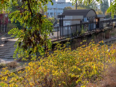 Suburban city train station with concrete platform and metal shed. Autumn colorful morning.