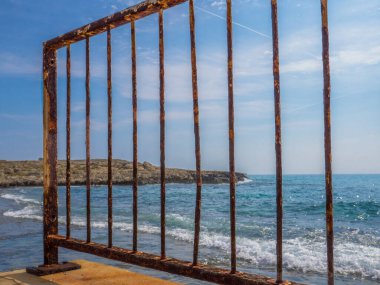 Kıbrıs Rum Kesimi 'nin başkenti Aye Napa' da güneşli bir günde Akdeniz üzerindeki paslı köprü çitlerinden ve kayalardan iskeleye bakın..