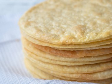 Napolyon pastası yapmaya hazır beyaz bir waffle havlusunun üzerinde pişmiş ince, yuvarlak tereyağlı bir yığın yakın çekim..