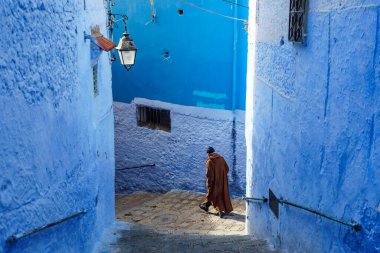 North Africa. Morocco. Chefchaouen. An old man dressed in a djellaba walking in a blue street of the medina