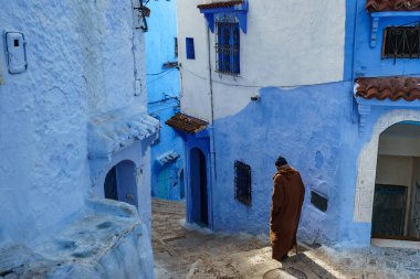North Africa. Morocco. Chefchaouen. An old man dressed in a djellaba walking in a blue street of the medina