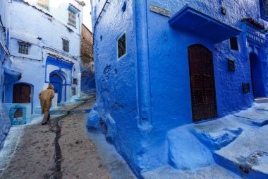 North Africa. Morocco. Chefchaouen. An old man dressed in a djellaba walking in a blue street of the medina