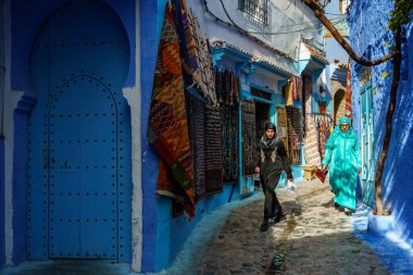 North Africa. Morocco. Chefchaouen. A women dressed in djellaba walking in a blue street of the medina