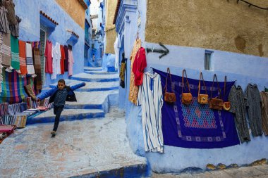 North Africa. Morocco. Chefchaouen. A young boy run in a typical decorated blue street of the medina