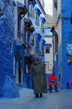 North Africa. Morocco. Chefchaouen. An old man dressed in a djellaba walking in a blue street of the medina