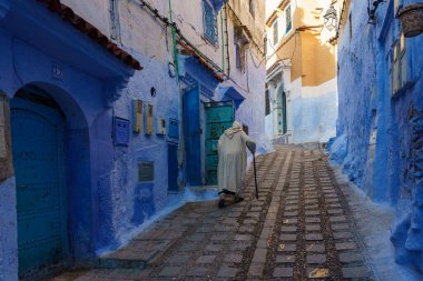 North Africa. Morocco. Chefchaouen. An old man dressed in a djellaba walking in a blue street of the medina
