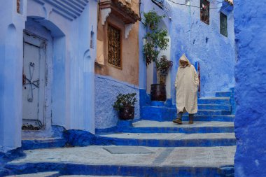 North Africa. Morocco. Chefchaouen. An old man dressed in a djellaba walking in a blue street of the medina