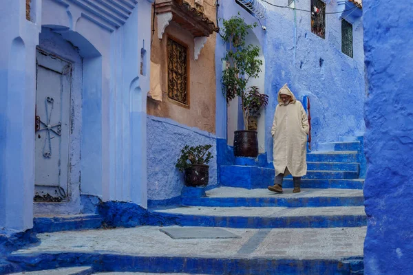 North Africa. Morocco. Chefchaouen. An old man dressed in a djellaba walking in a blue street of the medina
