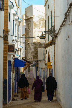 Fas 'ta. Essaouira. Djellaba giymiş üç kadın Medine 'de bir caddede yürüyor.