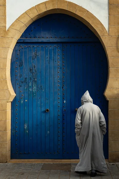Marrocos Essaouira Homem Vestido Djellaba Frente Uma Porta Azul Mesquita Imagens De Bancos De Imagens