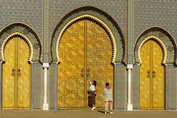 Fas 'ta. Fez. 1320 'de Merinidler tarafından kurulan kraliyet sarayının önünde bir turist. Alaouites Meydanı 'na 1970' lerde yerel bir zanaatkar tarafından bakır oyulmuş büyük kapılardan açılıyor..