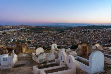 Fas 'ta. Fez. Fez 'deki eski Medine' nin yukarısındaki tepenin ilerisini ve gün batımında mezarları görün. Karaouiyine Camii 'nin merkezinde.