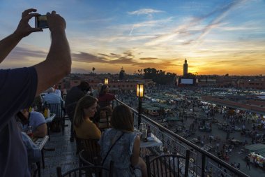 Kuzey Afrika. Fas 'ta. Marakeş. Gün batımında Jemaa El Fna Meydanı 'nda fotoğraf çeken insanlar.