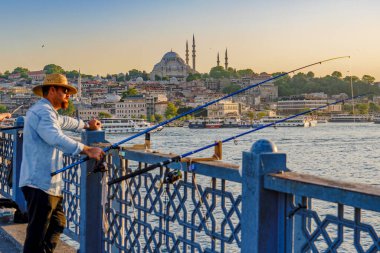 Hindi. İstanbul. Galata Köprüsü 'ndeki balıkçı ve alacakaranlıktaki Süleyman Camii veya Süleyman Camii.