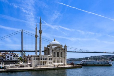 Hindi. İstanbul. Ortakoy Camii 'nin önüne mavi gökyüzünün altına bir yolcu gemisi yanaşıyor.