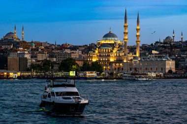 Hindi. İstanbul. Alacakaranlıkta aydınlanan Yeni Cami ve Boğaz 'ın önüne geç.