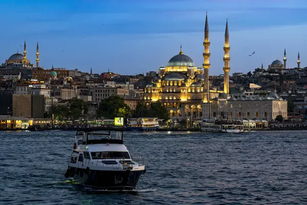 Hindi. İstanbul. Alacakaranlıkta aydınlanan Yeni Cami ve Boğaz 'ın önüne geç.