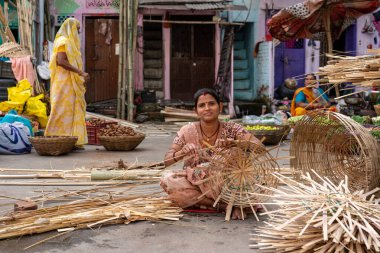 Hindistan. Rajasthan. Udaipur. Yerde oturan genç bir kadın hasır sepet yapmaya çalışıyor.