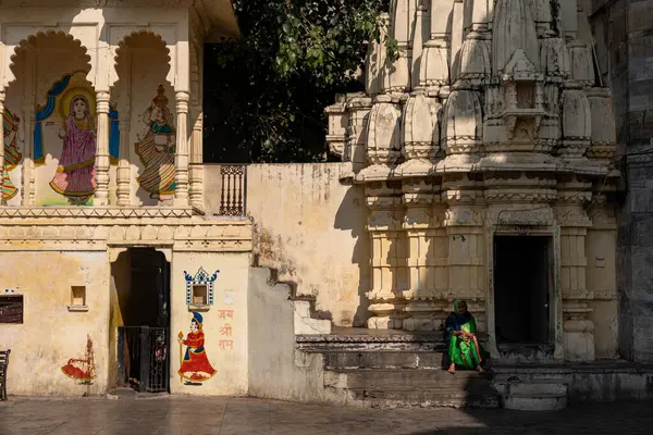 Hindistan. Rajasthan. Udaipur. Gangaur 'daki tapınağın merdivenlerinde oturan yaşlı bir Hintli kadın.