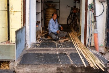 India. Rajasthan. Udaipur. A craftsman cuts bamboos used to make wicker baskets. clipart