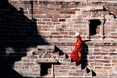 Hindistan. Rajasthan Eyaleti. Jodhpur. Kafasında kil sürahi taşıyan kırmızı sari giyen Hintli bir kadın Toorji Ka Jhalra 'nın merdivenlerinden çıkar (Toorji' nin Adım Kuyusu))
