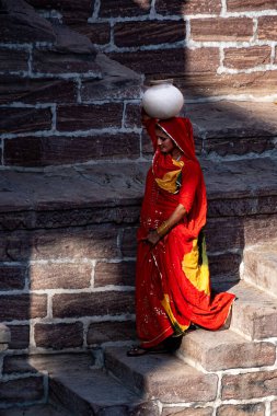 Hindistan. Rajasthan Eyaleti. Jodhpur. Kafasında kil sürahi taşıyan kırmızı sari giyen Hintli bir kadın Toorji Ka Jhalra 'nın merdivenlerinden aşağı iner.).
