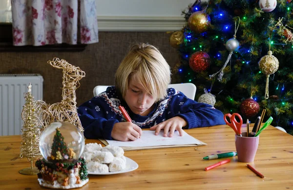 Geconcentreerde Jongen Schrijven Brief Aan Kerstman Met Kerstboom Achtergrond — Stockfoto