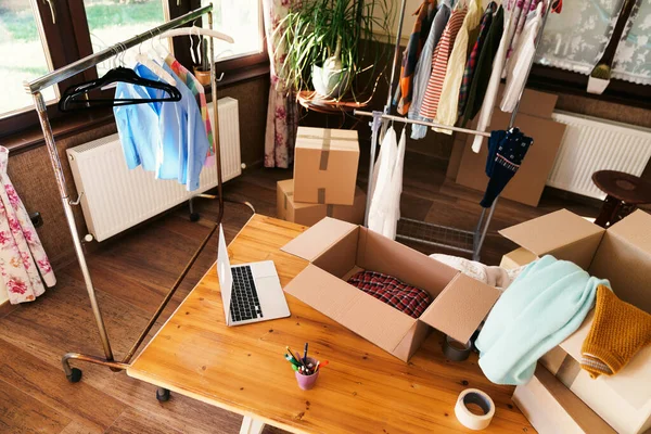 stock image High angle view of desk with cardboard box parcel with clothes, clothes resale concept.