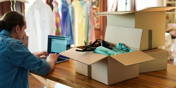 Cardboard boxes full with clothes inside, man sell or rent fashion online