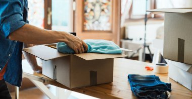 Kutunun içinde kıyafet paketleyen bir adam, kıyafet bağışlama konsepti..