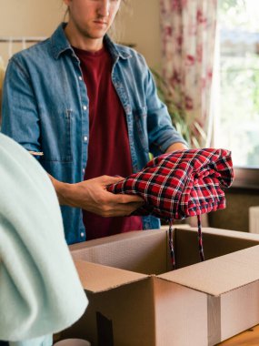 Adam kullanılmış giysiler, yeniden satma veya geri dönüşüm konseptiyle karton kutu hazırlıyor