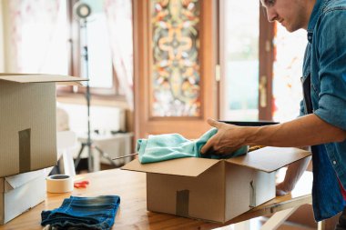 Kutunun içinde kıyafet paketleyen bir adam, kıyafet bağışlama konsepti..