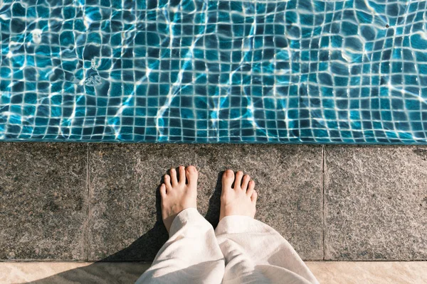 Person standing on the edge of swimming pool, top view
