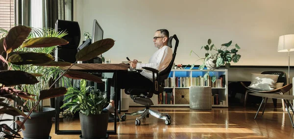 stock image Middle age man smiling while working from home and using phone.