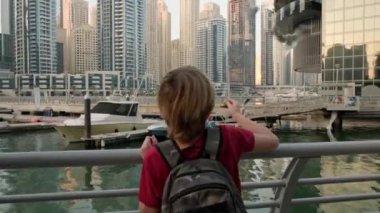 Cheerful cute boy laughing and feeding seagulls. Happy vacation in Dubai