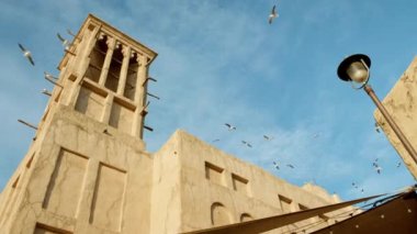 Local sandstone building and flying seagulls at Al seef in Dubai heritage district.