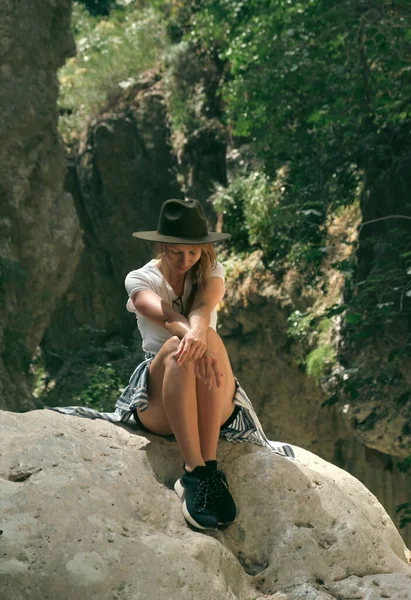 国家公园里戴着帽子坐在岩石上的女游客 — 图库照片