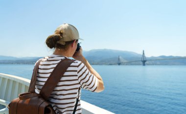 Büyük sırt çantalı bir fotoğrafçı gemiden denizin fotoğrafını çekiyor. Seyahat ve hobi kavramı