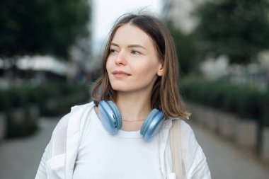 Mavi kablosuz kulaklıklı, gülümseyen genç kadın.