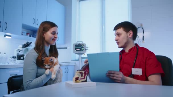 男兽医正在给养猫的女主人提一些建议和建议 病人手里拿着一只宠物 而猫则摸着她的脸 高质量的4K镜头 — 图库视频影像
