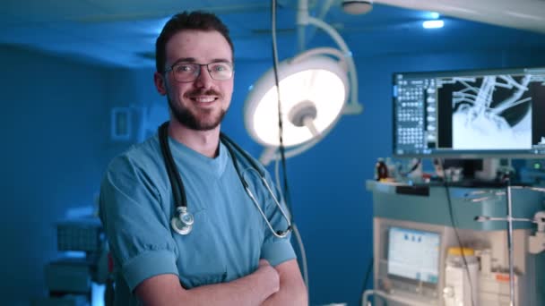 一位带着听诊器的兽医 脸上挂着灿烂的笑容看着摄像机 他身后有一个X光扫描仪 他是个了解自己工作领域的医学专家 — 图库视频影像