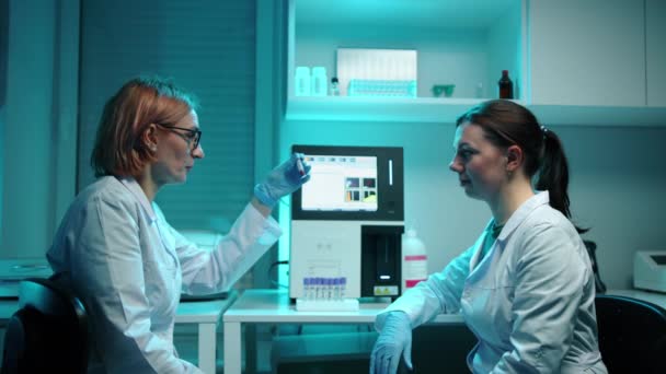 Wissenschaftlerinnen Laborkitteln Betrachten Ein Reagenzglas Mit Einer Roten Blutprobe Sie — Stockvideo