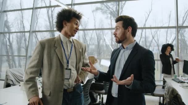 アフリカ系アメリカ人の男が白人 ひげを生やした同僚と話していた 現代のオフィス空間で新しいビジネス戦略を議論する仲間 高品質4K映像 — ストック動画