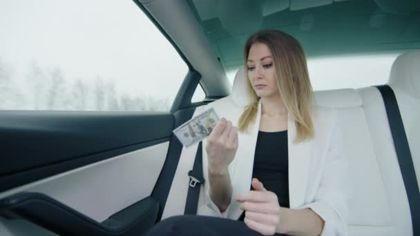 白い車の後部座席の半分で100ドル札を引き裂く動揺した実業家 ビジネススーツの女性は車の窓の外を見る 高品質4K映像 — ストック動画